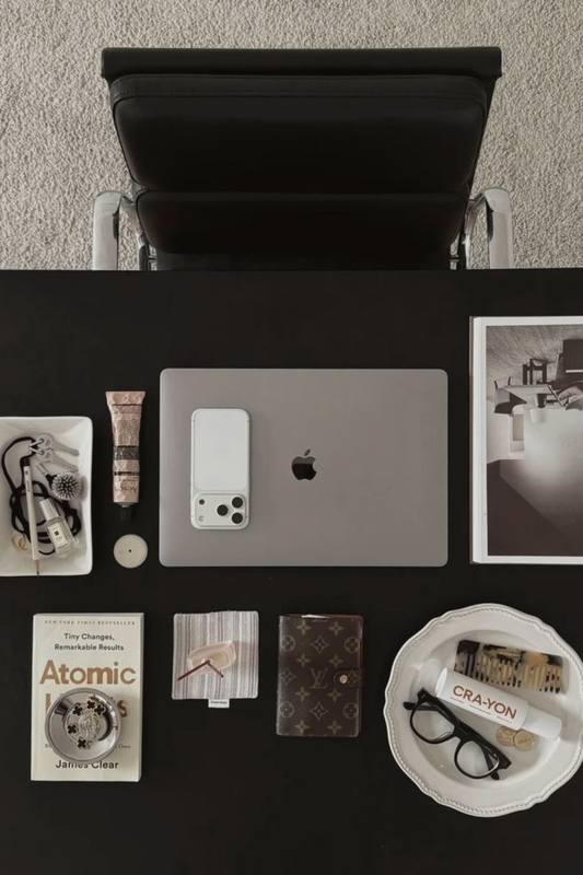 Overhead view of a creative workspace with laptop, books, accessories, and curated design details. 