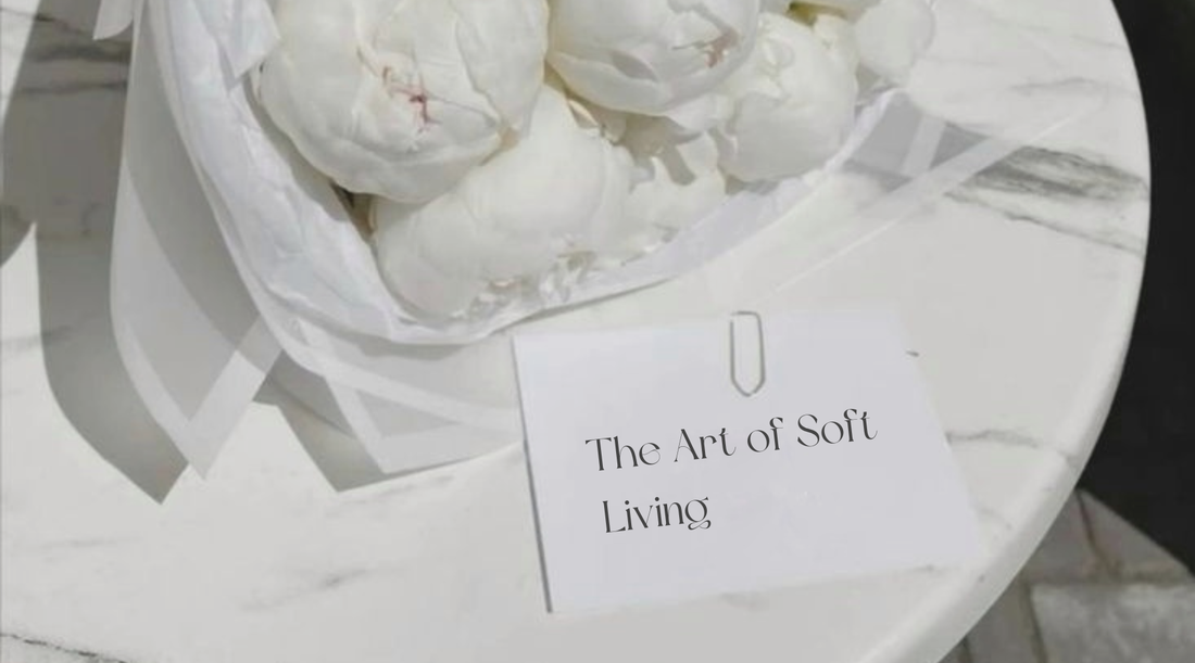 Minimal marble table styling with white flowers and a soft luxury lifestyle card reading “The Art of Soft Living,” inspired by calm and elegant living by Mirrorina. 